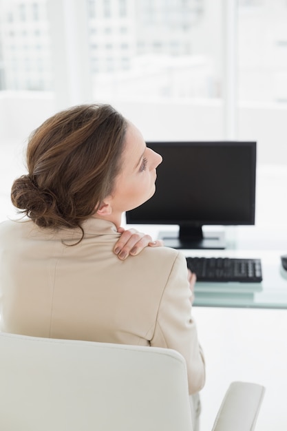 Foto donna di affari con dolore al collo davanti al computer in ufficio