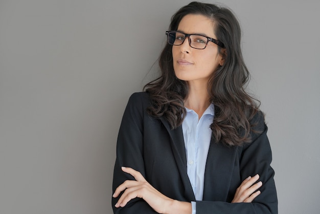 Businesswoman with spectacles standing on grey 