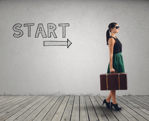 Businesswoman with suitcase ready to walk in the direction of the arrow