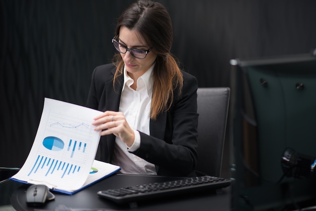 Foto donna di affari sul lavoro nel suo ufficio della società che legge documenti