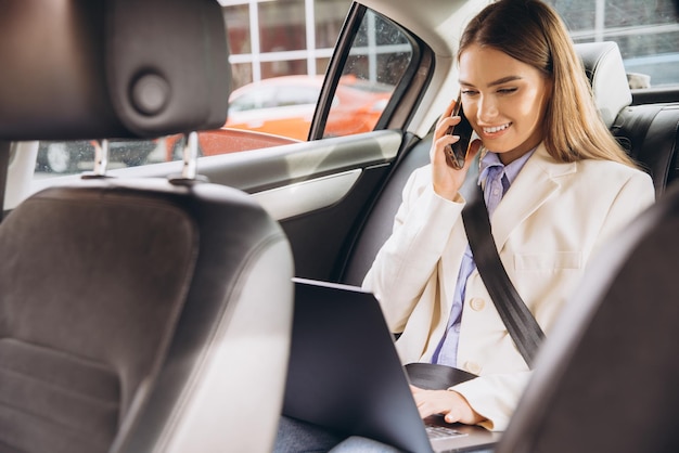 Businesswoman Working in Car Using Laptop and Phone