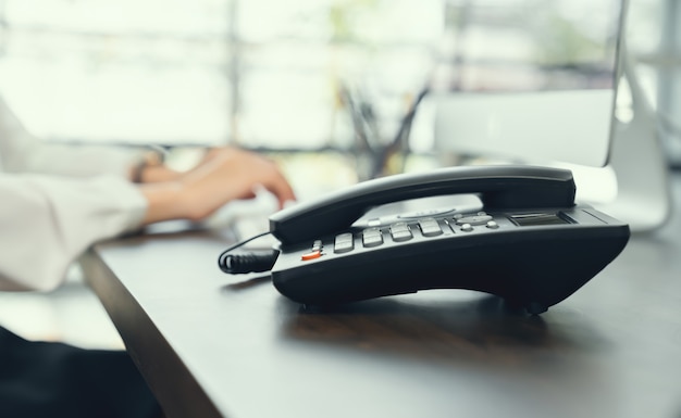 Photo businesswoman working on computer and office phone on the desk.	