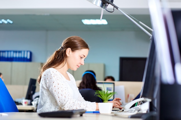 Businesswoman working at desk in front of laptop in office