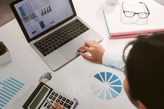 Businesswoman working on desk using calculator and laptop analyzing finance accounting in office