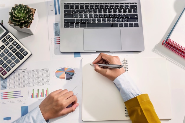 Businesswoman working on desk using calculator and laptop analyzing finance accounting