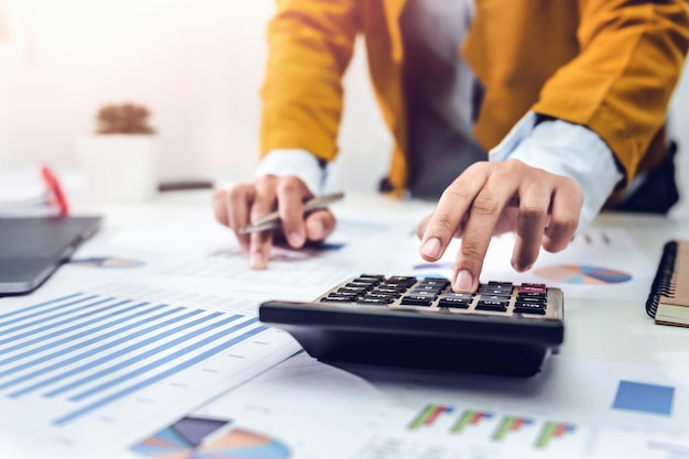 Businesswoman working on desk using calculator and laptop analyzing finance accounting