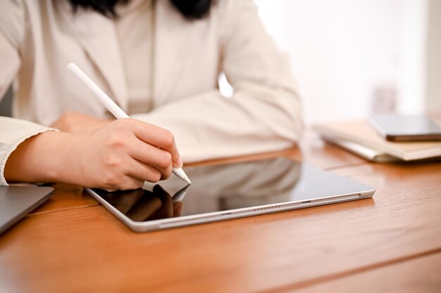 Una donna d'affari che lavora al suo compito utilizzando il touchpad della tavoletta digitale per progettare il suo processo di lavoro