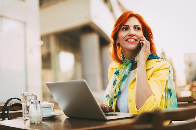 Businesswoman working at the laptop on a coffee break in a street cafe.