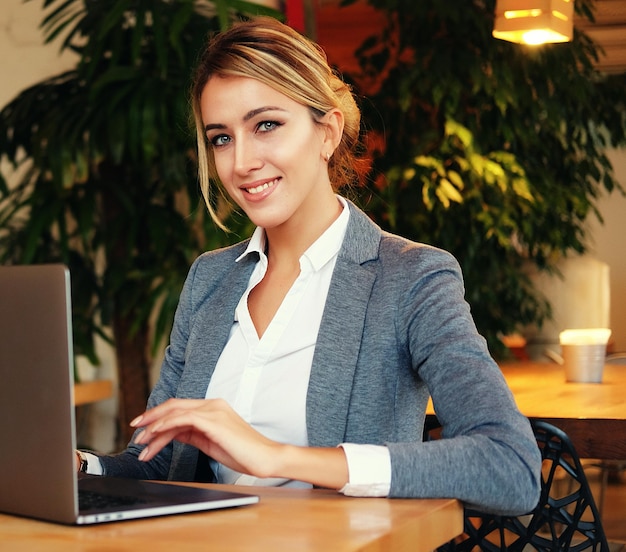 Donna di affari che lavora sul computer portatile nella caffetteria giovane donna d'affari utilizza il computer portatile nel concetto di caffè e di affari di stile di vita