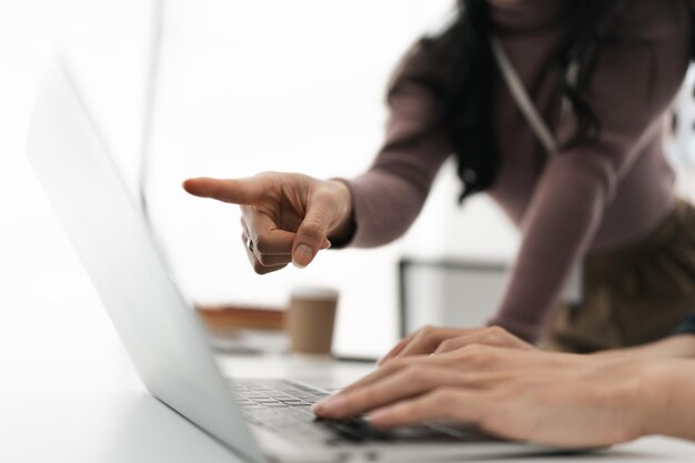 Businesswoman working on laptop computer on office table with person teaching