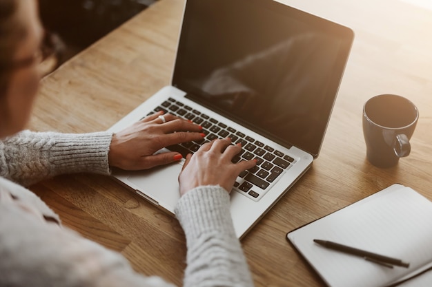 Photo businesswoman working on a laptop computer sitting at home and managing her business via home office, closeup