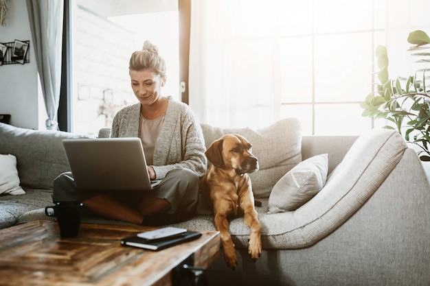 Donna d'affari che lavora al computer portatile seduta a casa e gestisce la sua attività tramite l'ufficio domestico