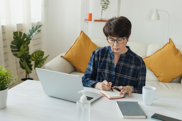 Businesswoman working on laptop computer sitting at home in pajama home wears and managing her business via home office during Coronavirus or Covid19 quarantine