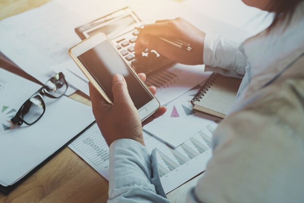 Businesswoman working in office on desk using calculator with telephone.