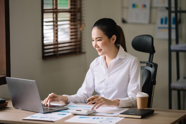 Деловая женщина, работающая в офисе с рабочим блокнотом, планшетом и ноутбуком