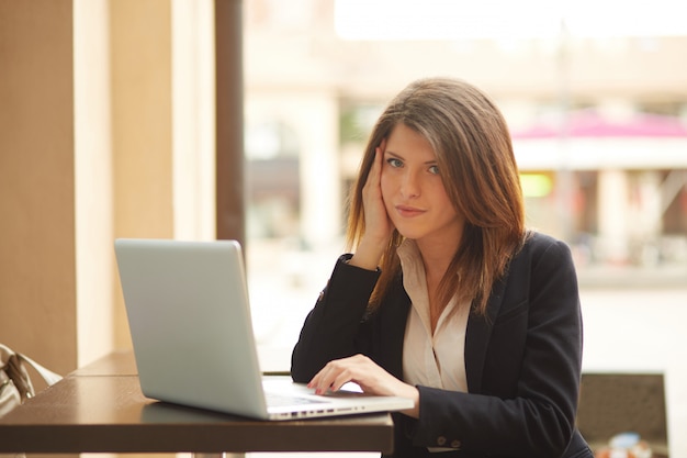 Donna di affari che lavora fuori dell'edificio per uffici con i dispositivi digitali