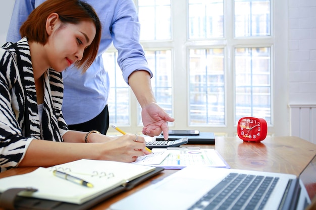 Photo businesswoman working while male colleague using calculator at desk in office