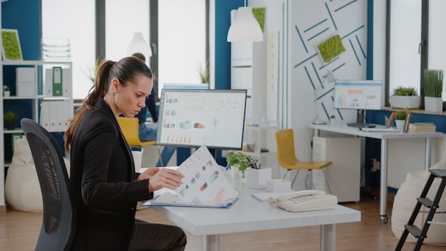 Businesswoman working with computer and data charts on paper, using technology for development and management. Entrepreneur planning marketing strategy for successful finance company