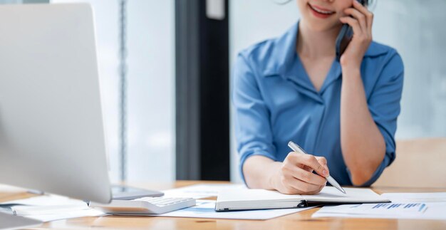 Businesswoman writing business papers at desk in modern coworking office copy space