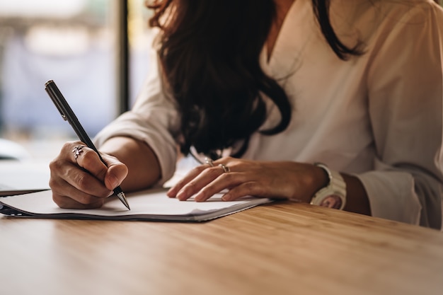 businesswoman writing on paper at workplace. young woman handwriting note at office.