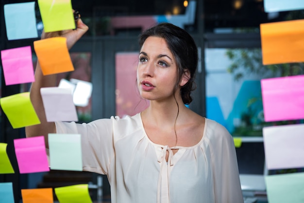 Businesswoman writing on sticky note