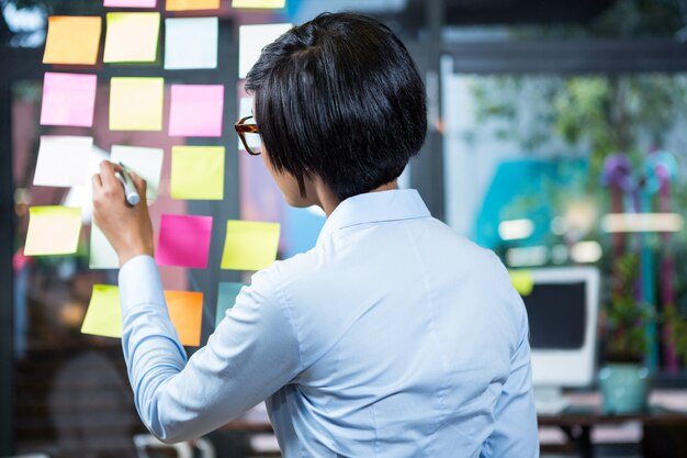 Businesswoman writing on sticky note