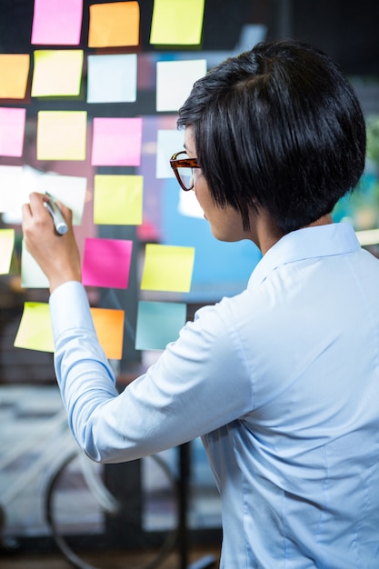 Businesswoman writing on sticky note