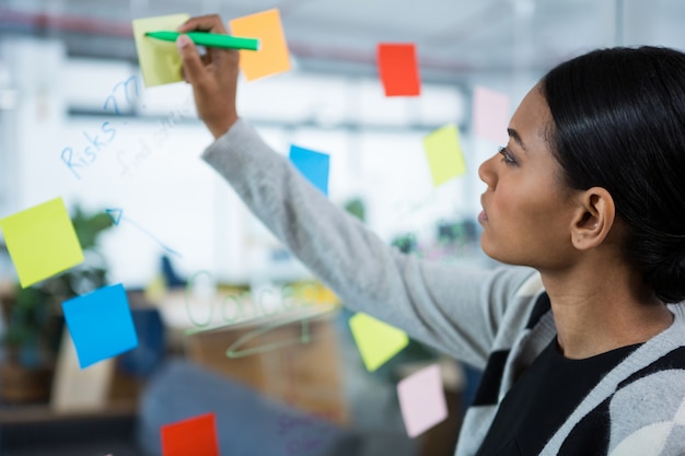 Businesswoman writing on sticky notes