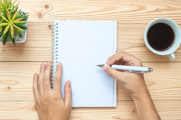 Businesswoman writing with notebook, black coffee cup