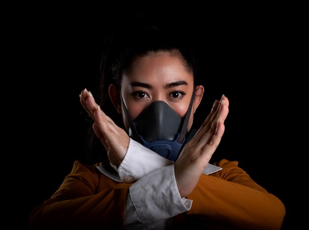 Businesswoman of young Asia woman putting on a respirator N95 mask to protect from airborne respiratory diseases , Women is hand sign stop