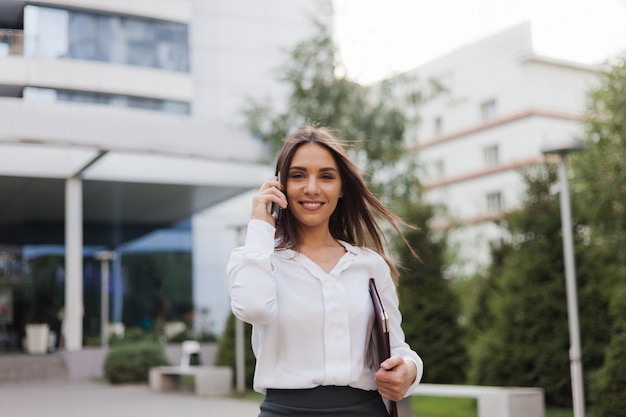 Foto imprenditrice. giovane manager femminile che indossa una gonna e una camicetta parlando al telefono