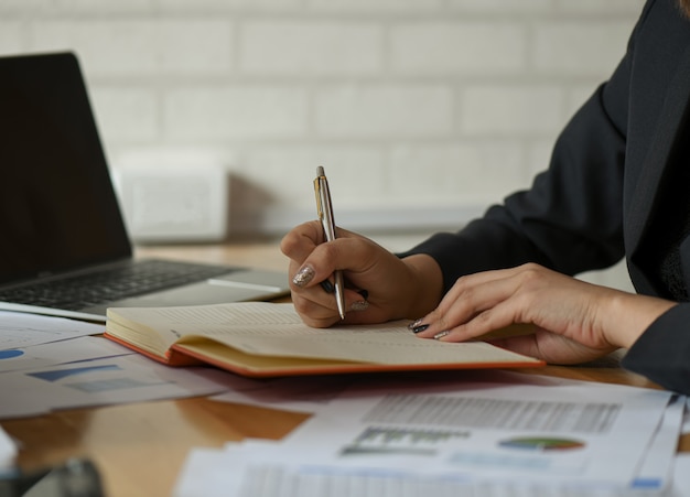 Businesswomen are taking notes of work on the desk in the office.