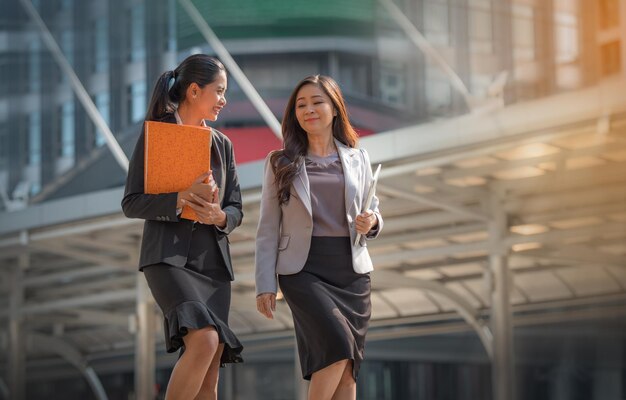 写真 都市のオフィスビルに向かって歩きながら話し合っている女性ビジネスマン