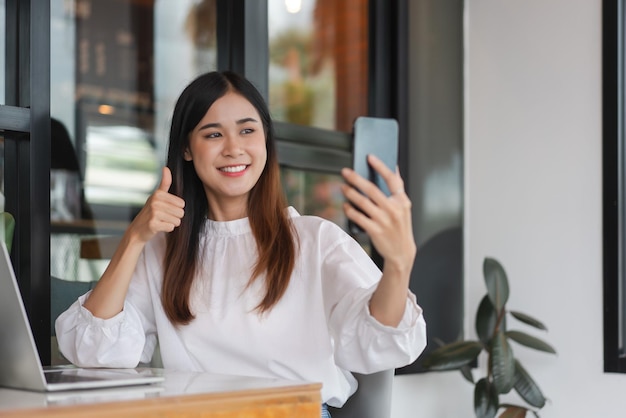 Businesswomen making thumb up gesture with colleague in video call while working in outside office