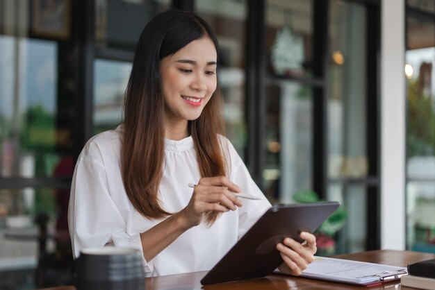 オフィスの外で働いている間,タブレットでビジネスデータを読み,メモを取る女性ビジネスマン