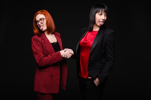 Photo businesswomen showing disgust while shaking handsbusiness partners showing dislike to their business