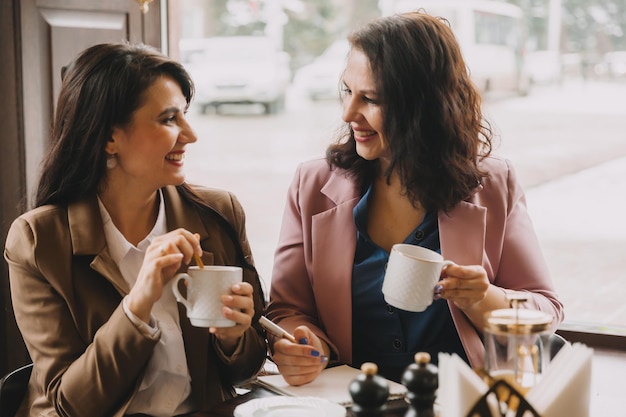 Businesswomen sit in a cafe drink coffee and have a business
conversation discuss business and have fun