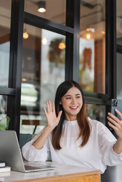 Photo businesswomen use smartphone to greeting with colleague in video call and working in outside office