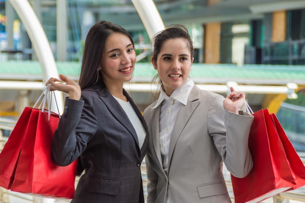 Photo businesswomen with shopping bags standing on bridge in city