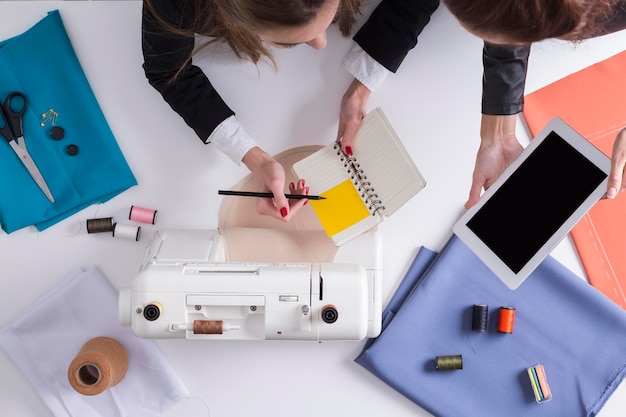 Businesswomen with tablet and notebook are about to start sewing