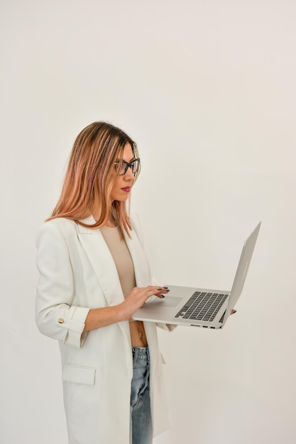 Photo bussines woman in a white jacket holdind a gray laptop