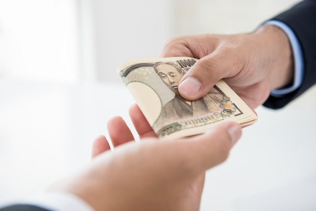 Bussinessman passing Japanese yen money to his partner