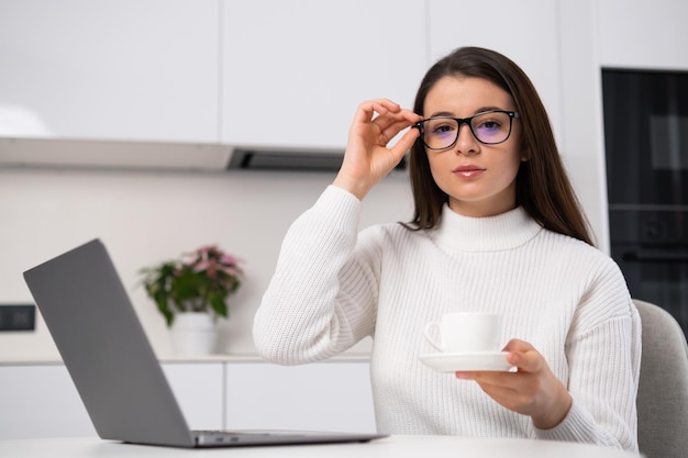 Bussinesswoman die haar bril aanpast en een kopje koffie vasthoudt