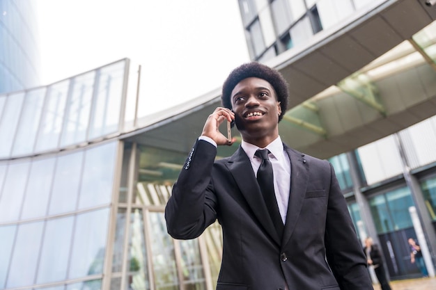 Busy african businessman talking to the mobile while commuting in the city