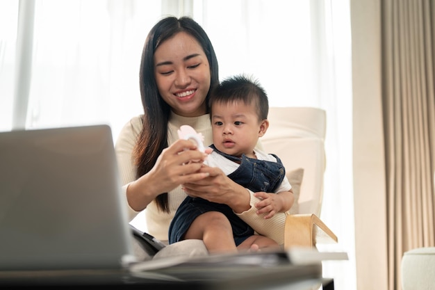 A busy Asian working woman mom is focusing on her work and taking care of her cute little son