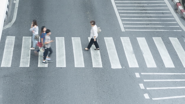 写真 にぎやかなぼかし人々は街の通りで交差点の標識を越えて速く歩きます。