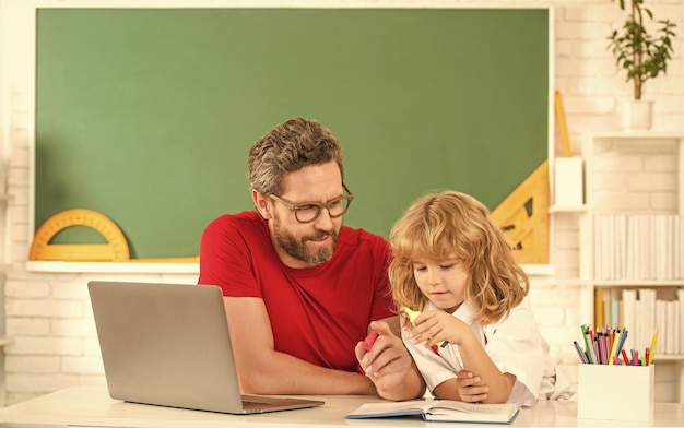 Занятый мальчик учится с частным учителем, вебинар, видеоурок, онлайн-обучение на ноутбуке, отец и сын используют современные коммуникационные технологии, семейный блог, детство и отцовство.