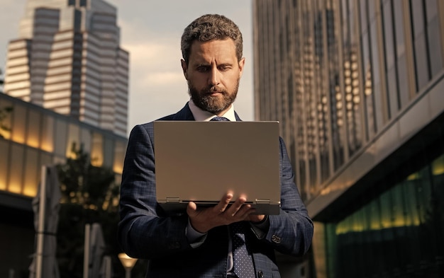 Busy businessman working online on laptop outside the office business