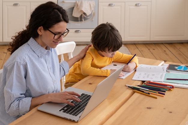 Busy businesswoman works from home next to his son