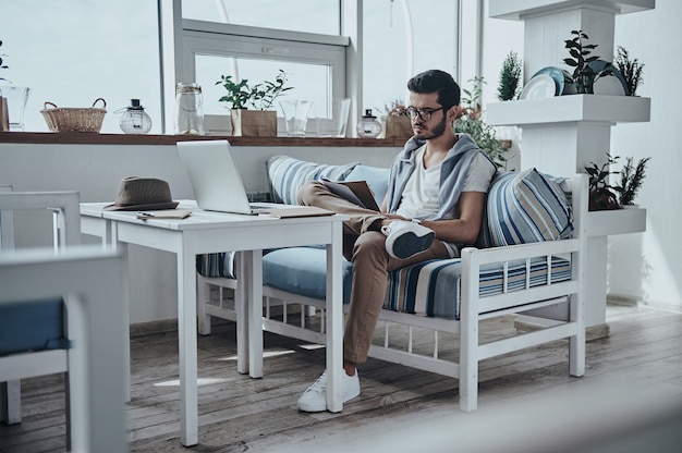 Busy day. Thoughtful young modern man holding some papers and looking at it 